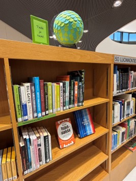 kirjaston ympäristöhyllyn koristeena on vihersävyinen maapallo ja kyltti: Tutki ja toimi. Hyllyssä on monipuolisesti esillä ympäristöaiheista kirjallisuutta.